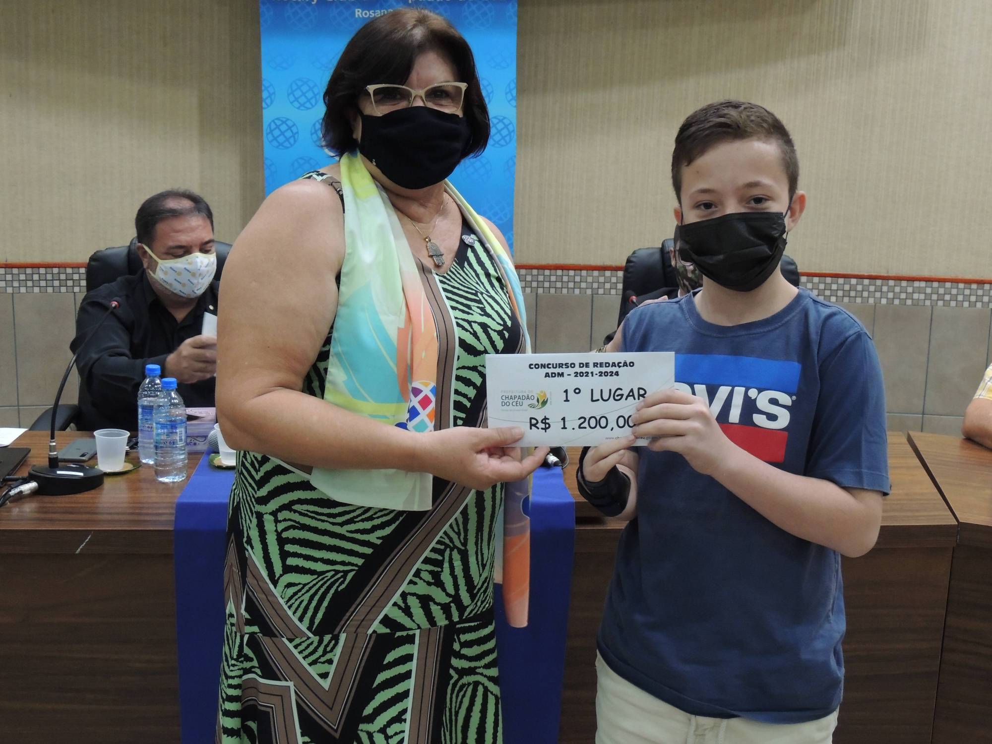 Rotary Club de Chapadão do Céu realizou no dia 26 de agosto, a primeira reunião festiva da gestão 2021 - 2022 para entrega solene da premiação do primeiro concurso de redação com o tema: Chapadão do Céu, terra de sonhos e oportunidades. O tema escolhido foi para prestigiar o aniversário de 39 anos da cidade e teve como público alvo, os alunos do Ensino Fundamental, das séries dos nonos anos das escolas municipais e particulares do município. Foram selecionadas três redações com premiações de primeiro lugar, que ficou com o aluno do Colégio Alicerce chamado Victor Hugo de Almeida Konig. O segundo lugar ficou com a aluna da Escola Dona Amélia, estudante do Eja, chamada Francisnaile de Santos Silva e o terceiro lugar, também da Escola Dona Amélia, ficou com a aluna Késsile Maiara Souza .Além dos premiados, fizemos sorteios para que mais alunos fossem contemplados com brindes e as professoras também receberam flores como forma de agradecimento pelo empenho e dedicação com os alunos. O Rotary Club agradece a parceria da Prefeitura Municipal, pelo apoio cultural, agradece a Secretaria de Educação por acreditar no nosso evento, e a equipe de Projetos do clube, pela proposta e pela realização das etapas do concurso. Agradecemos também a CAC pela continuação do Projeto com a publicação de 5 mil exemplares das redações produzidas e a Secretaria de Cultura e Turismo pela proposta de realizar uma peça teatral com a redação vencedora. Agradecemos ainda às Escolas, às professoras, aos alunos e a todos, que de uma forma ou de outra, estiveram envolvidos neste lindo evento, que será o primeiro de muitos envolvendo a comunidade céu chapadense.