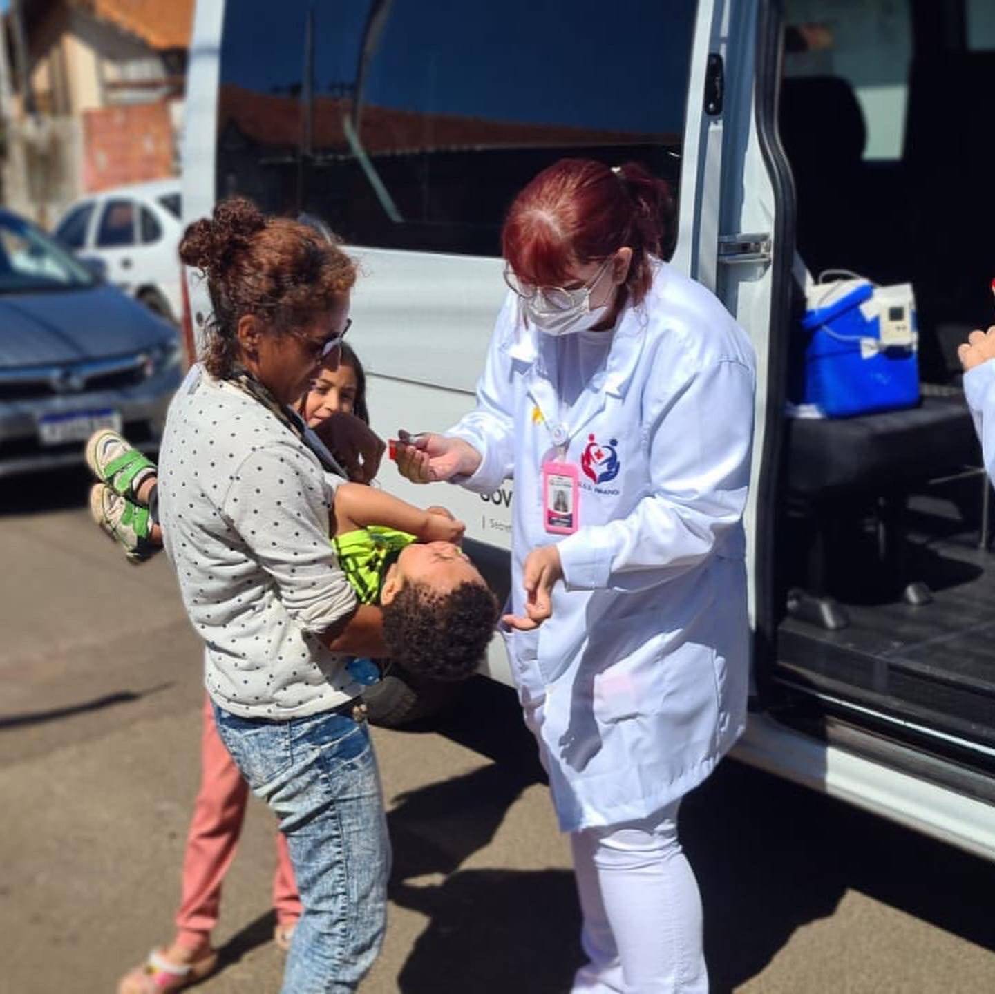 Ambulância com as doses de vacina passando de casa em casa 