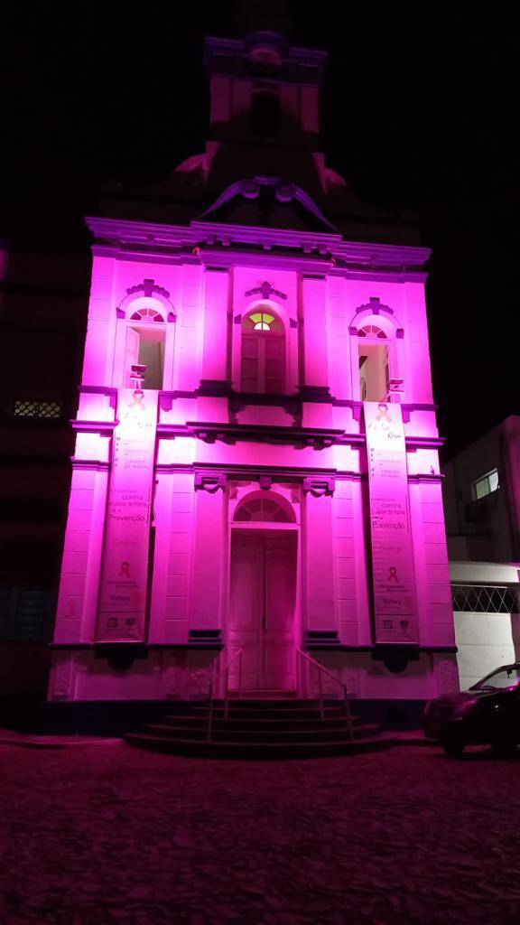 Fachada da Capela da Santa Casa de Bagé com faixas e iluminação em apoio ao Outubro Rosa