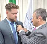 Fábio recebendo do seu padrinho de Rotary, Natan, o distintivo de Rotary