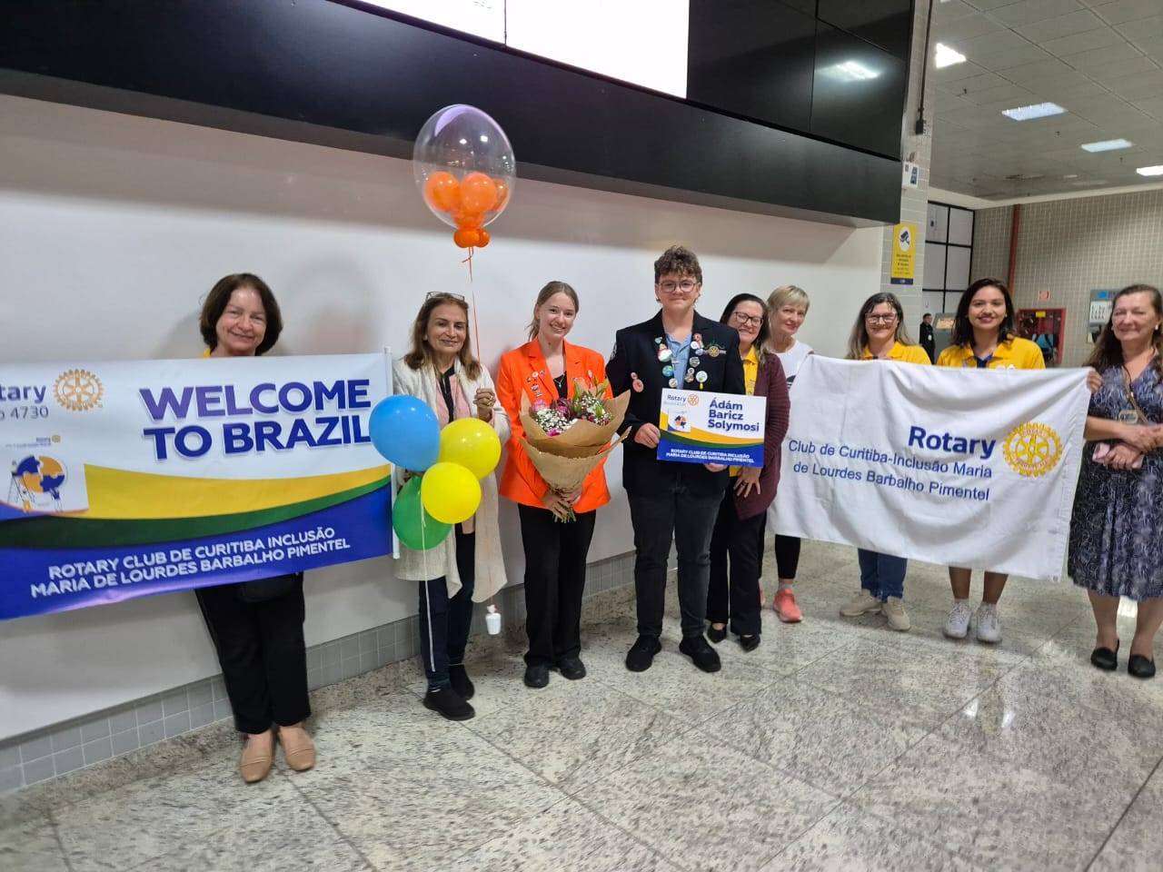 Membros do Club e família hospedeira com o intercambista Adam