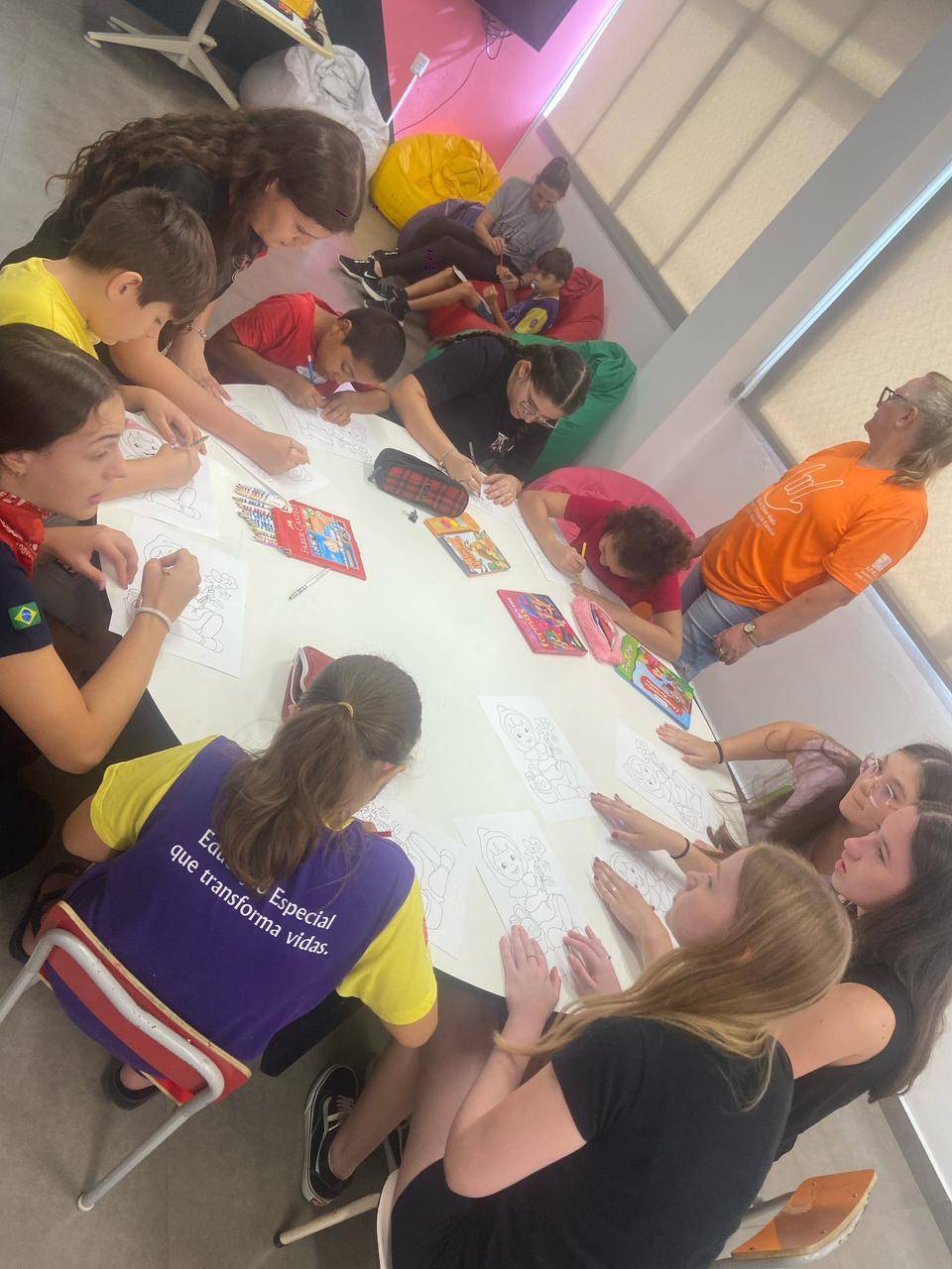 a imagem apresenta os interactianos com as crianças fazendo desenhos e colorindo-os.