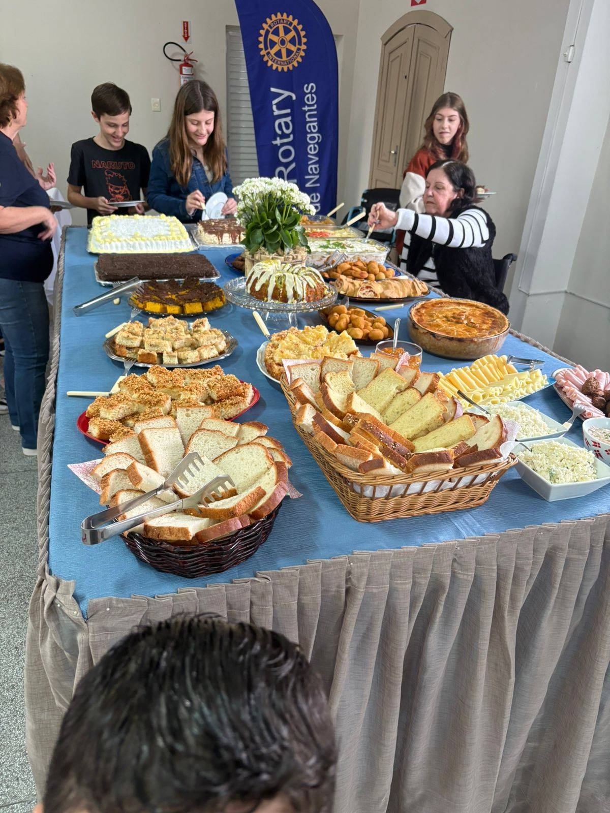 Mesa do café colonial com as pessoas se servindo