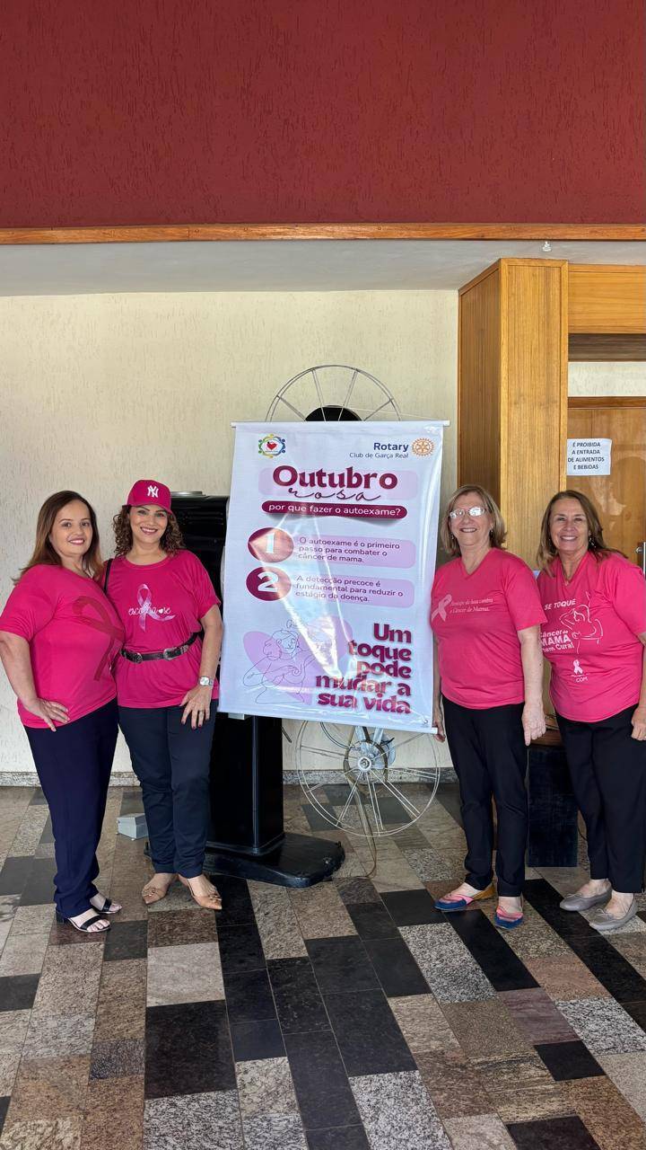Integrantes da Casa da Amizade durante a ação do Outubro Rosa, com o banner da campanha em destaque.