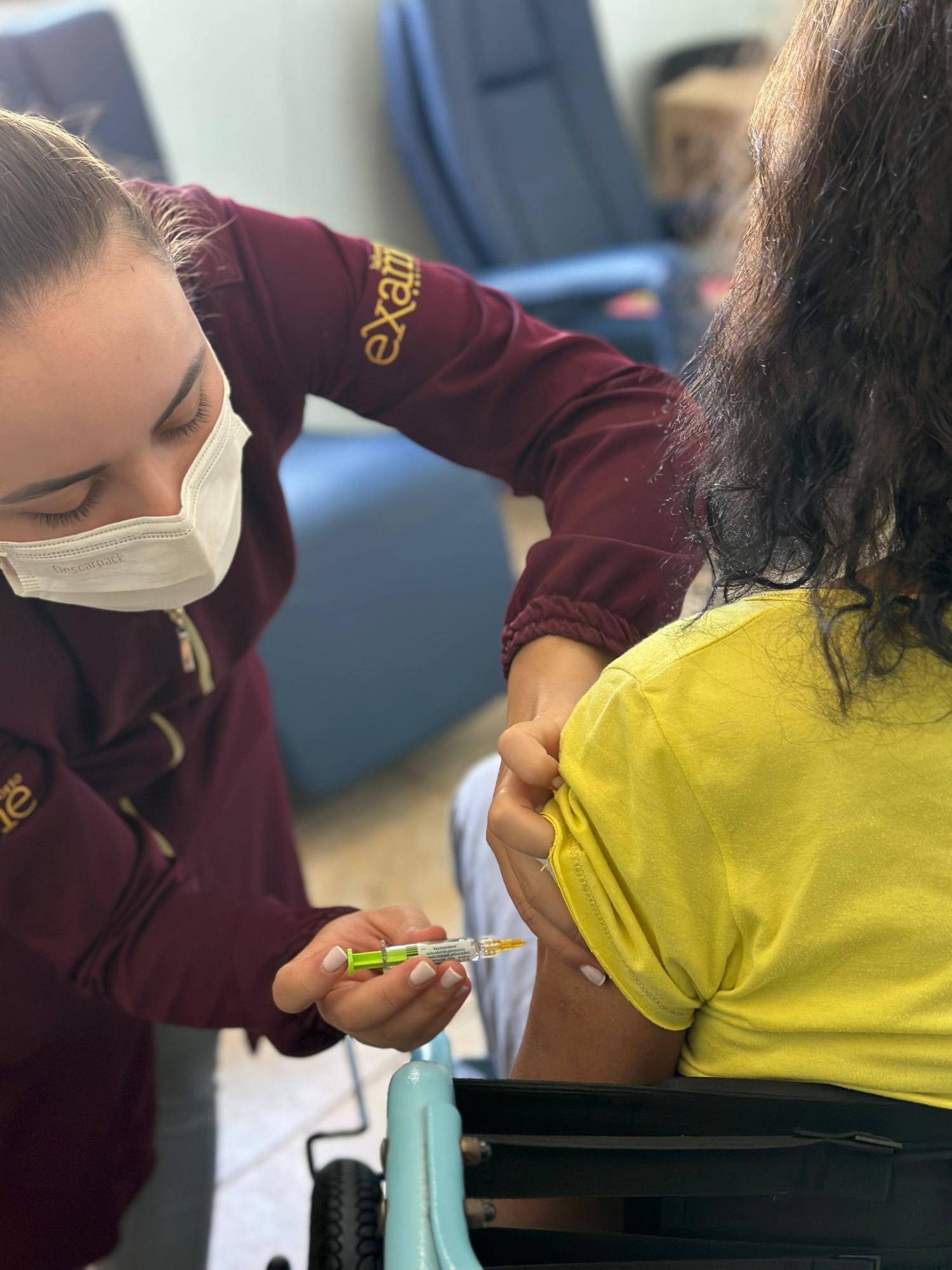 Funcionária do Laboratório Exame + Vacinas, fazendo a vacinação em um idoso. 