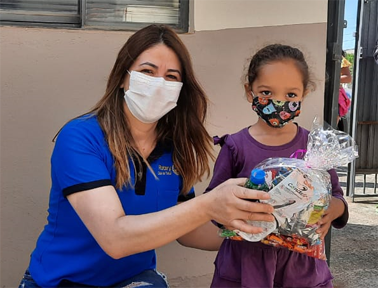 Vanilda Barros, presidente da CA, entregando um kit para criança